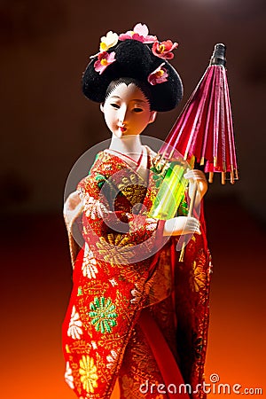 Japanese female kimono doll wearing red paper umbrella with flowers in hair and green glowing tritium trinket Stock Photo